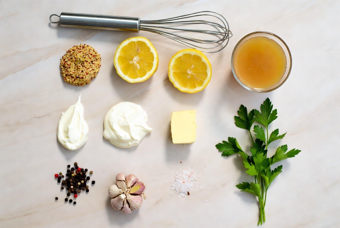 Ingredients for Dijon lemon cream sauce including lemon, Dijon mustard, garlic, cream, butter, and parsley