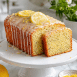 Glazed lemon poppy seed pound cake with sliced moist crumb and fresh lemon garnish