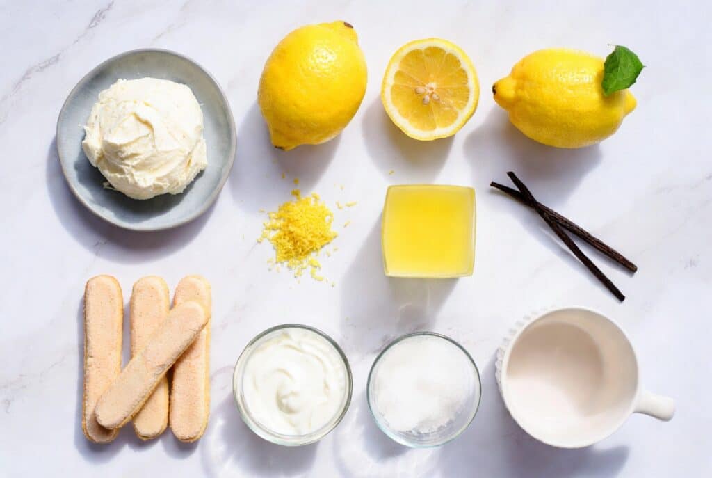 Lemon tiramisu served in small glasses with creamy mascarpone layers, lemon slices, and fresh mint